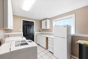 Laundry room featuring cabinet space, washer and clothes dryer, and light tile patterned floors