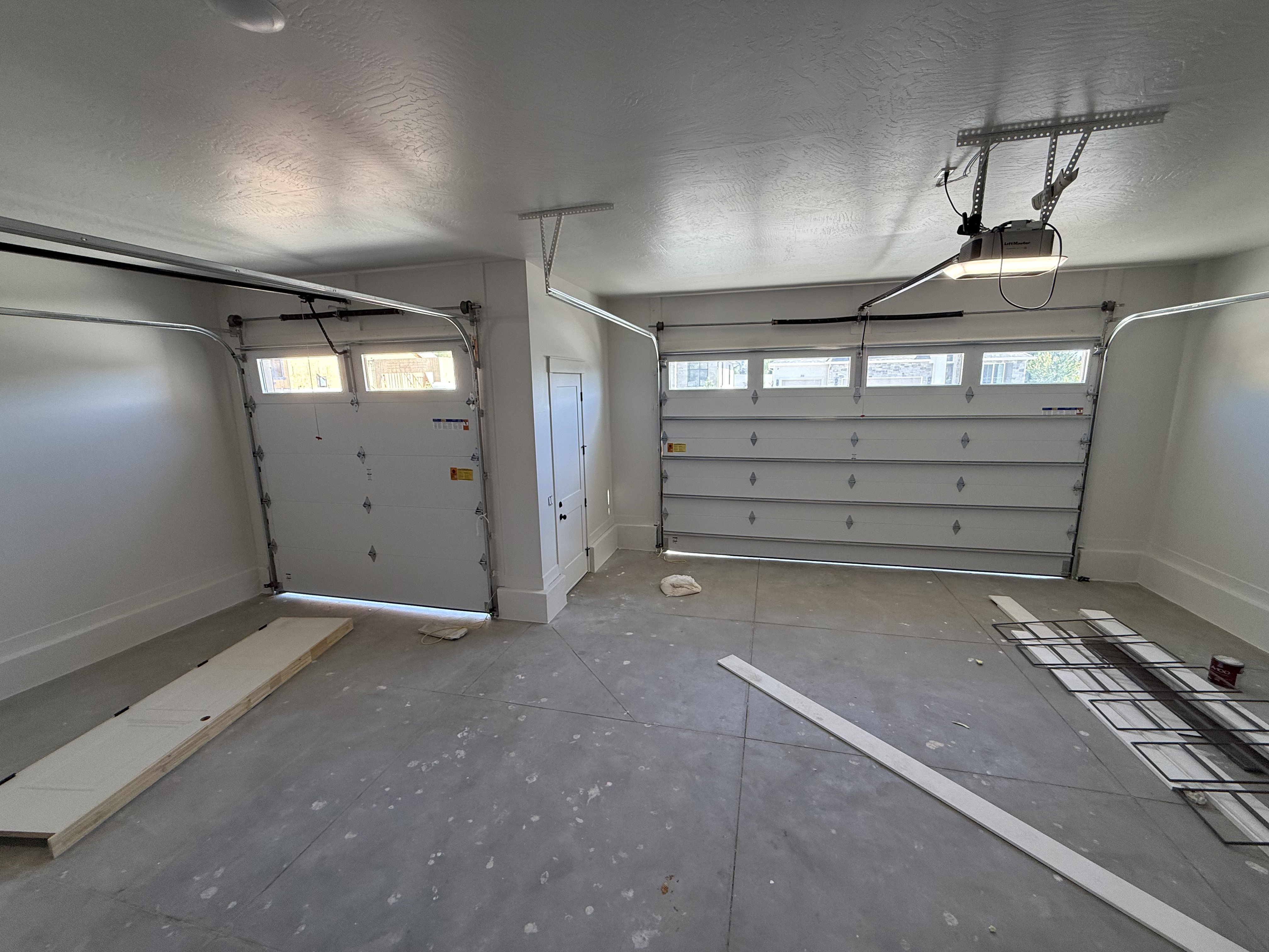 Two-car garage with concrete flooring, two overhead garage doors with window panels, and automatic garage door openers