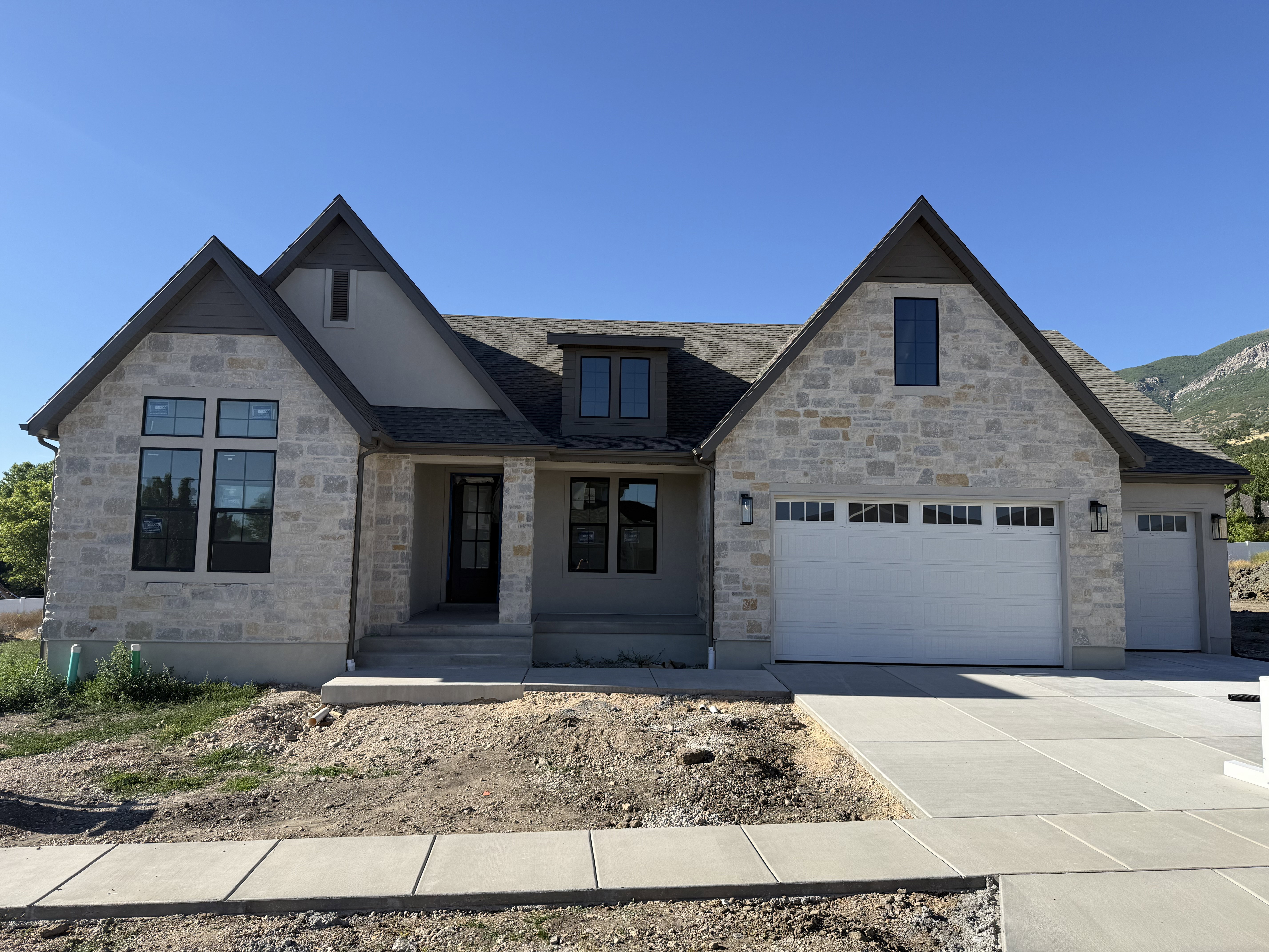 Stone and stucco exterior with multiple gables and a dark gray shingle roof