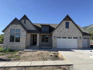 Stone and stucco exterior with multiple gables and a dark gray shingle roof