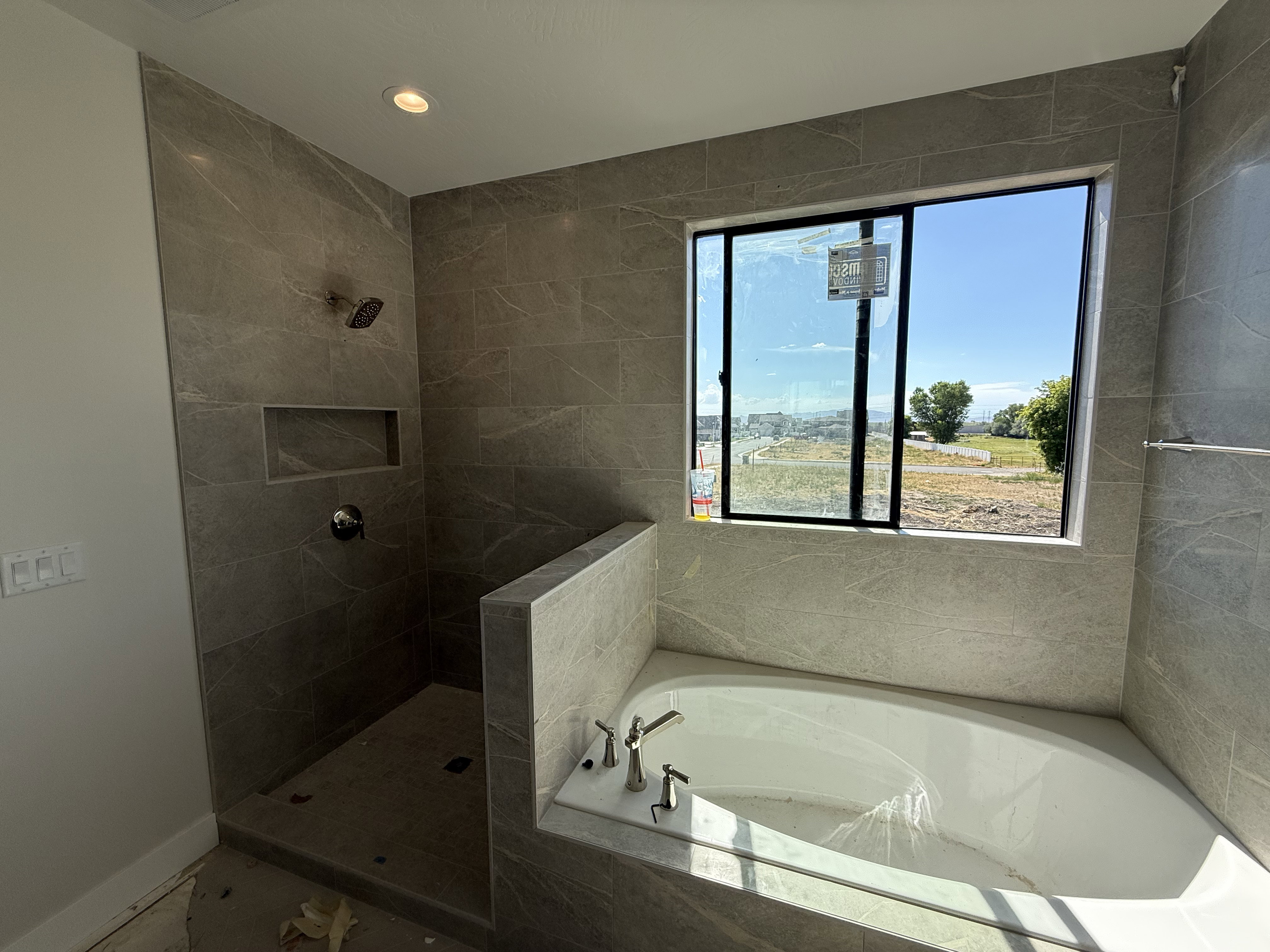 Tiled shower enclosure featuring a recessed niche and rain shower head