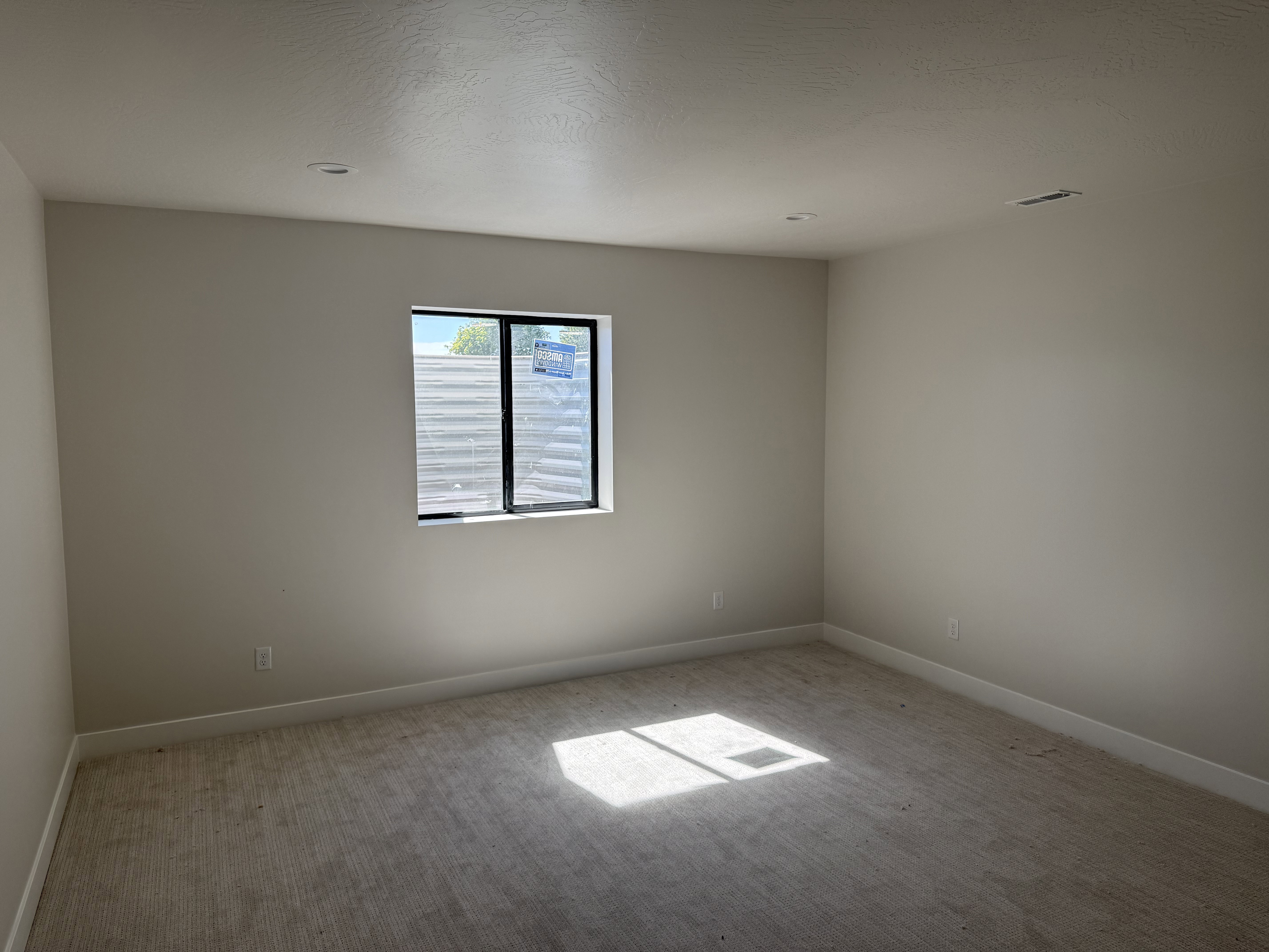 Carpeted room featuring a window with black trim, recessed lighting, and light-colored walls