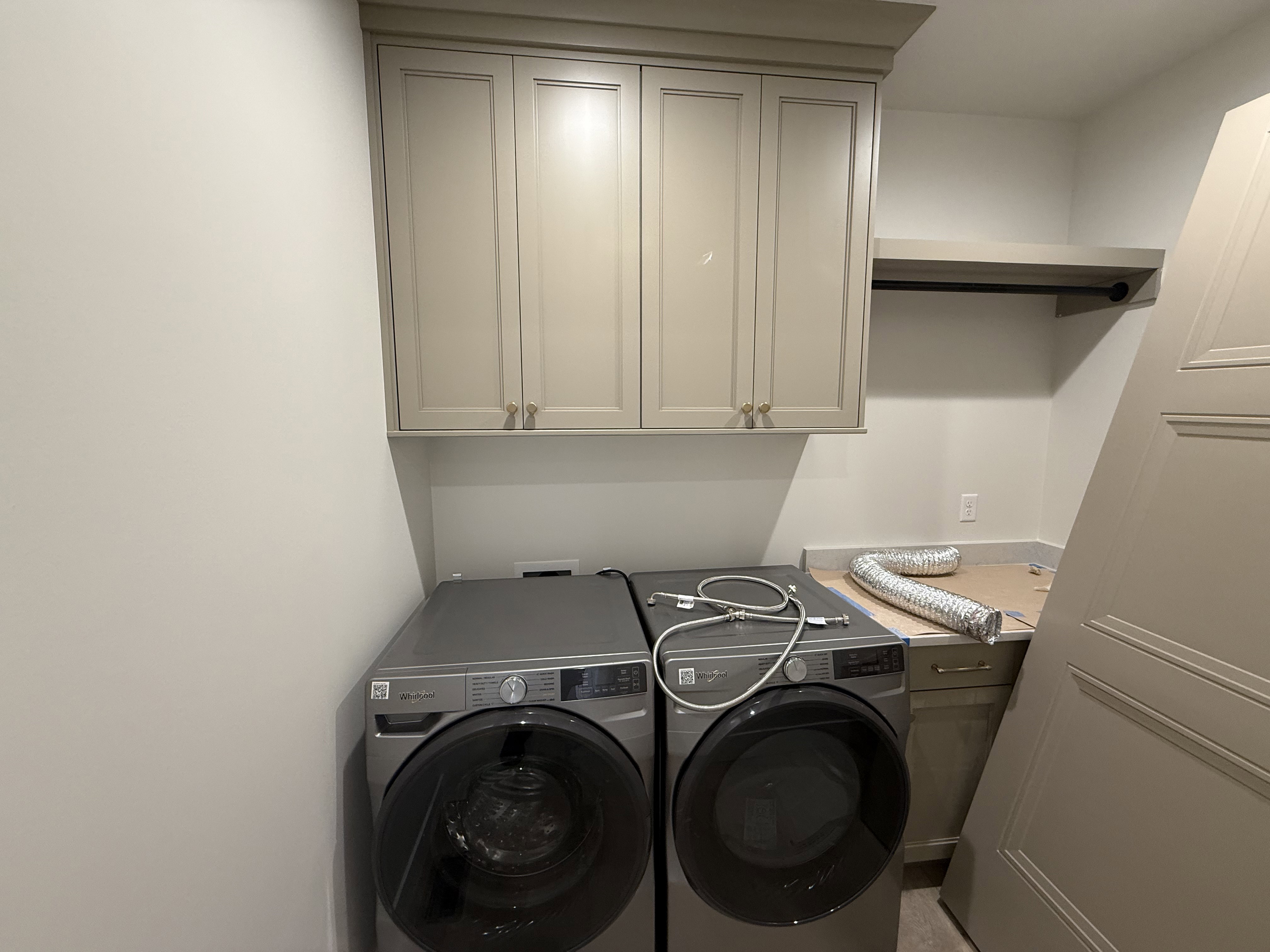 Laundry room featuring upper cabinetry with crown molding, a built-in hanging rod, and a countertop space