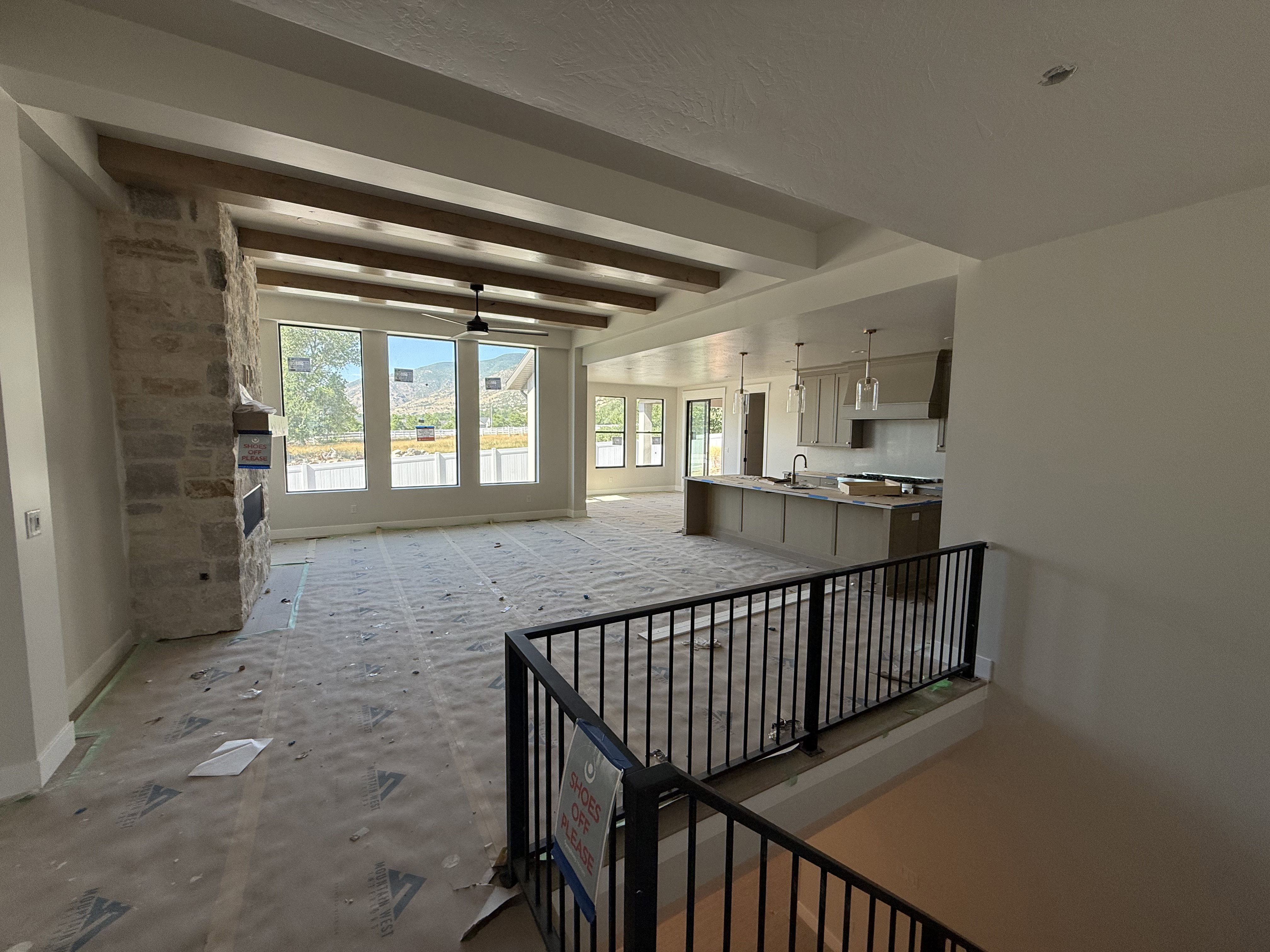Open-concept living area featuring a stone-clad fireplace and wood-look ceiling beams
