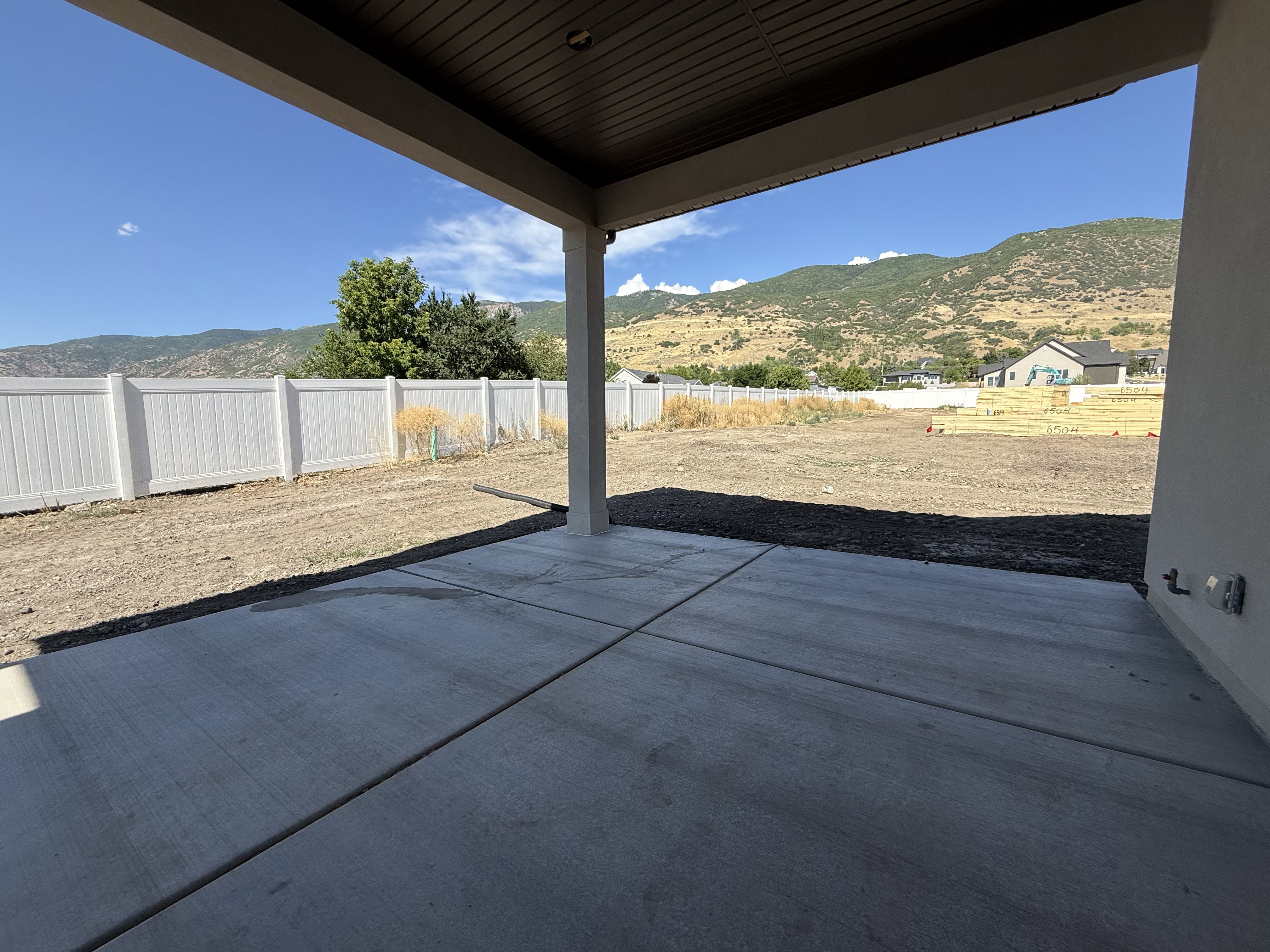Expansive concrete patio with overhead coverage, supported by a single column