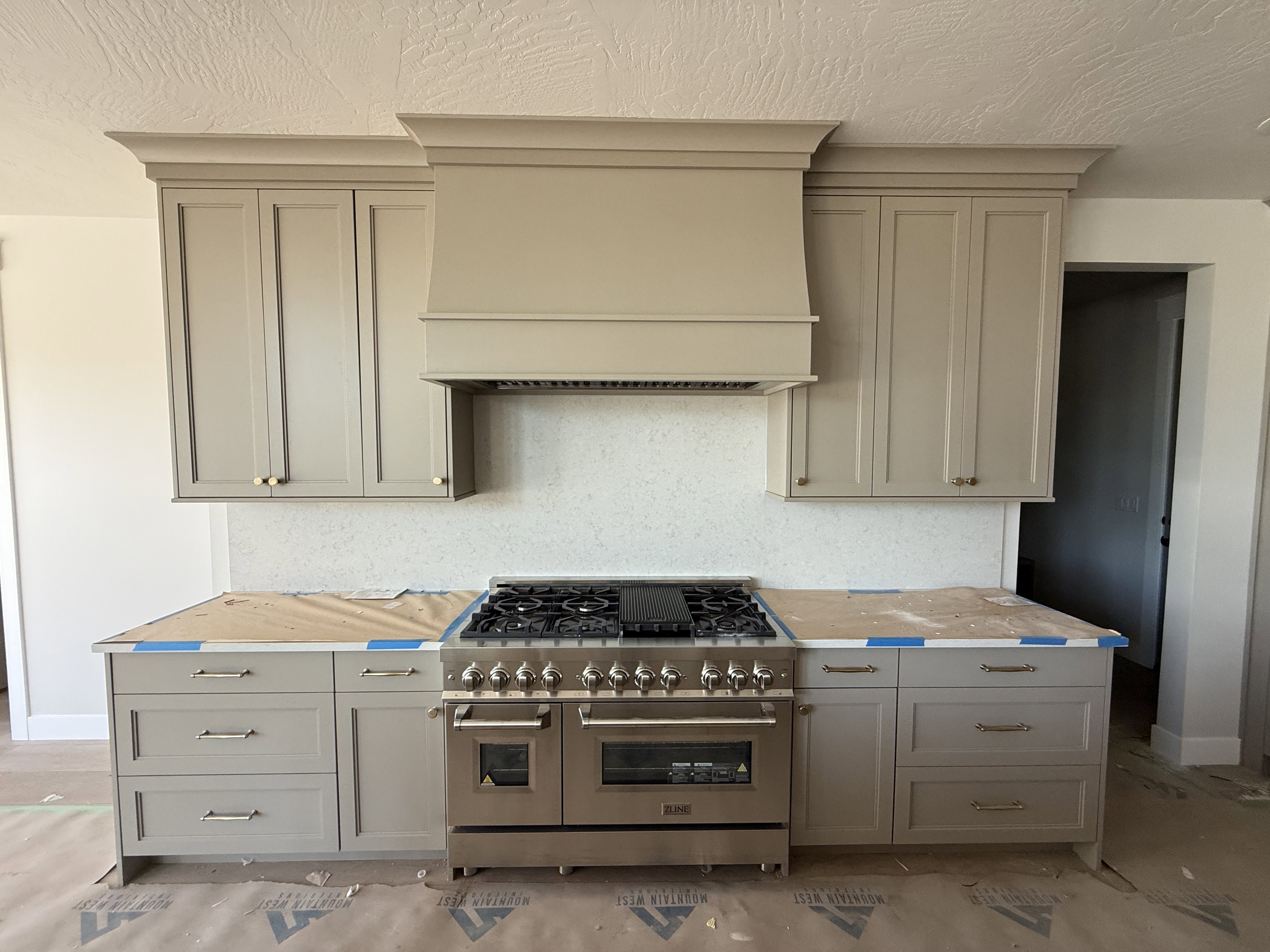 Professional-grade range with multiple burners and double ovens, integrated below a custom-designed range hood