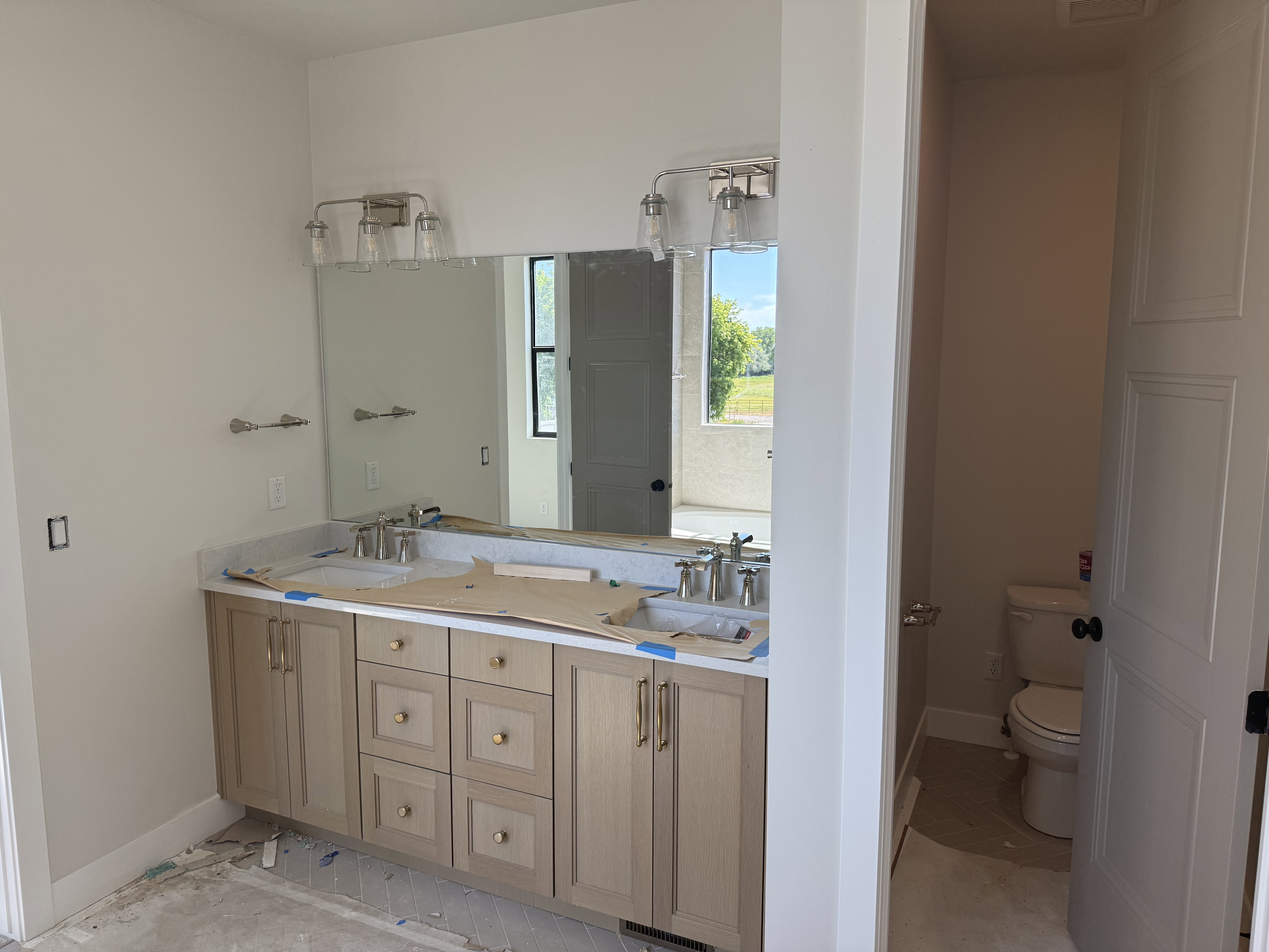 Dual vanity with light wood-finish cabinetry, neutral countertop, and integrated sinks
