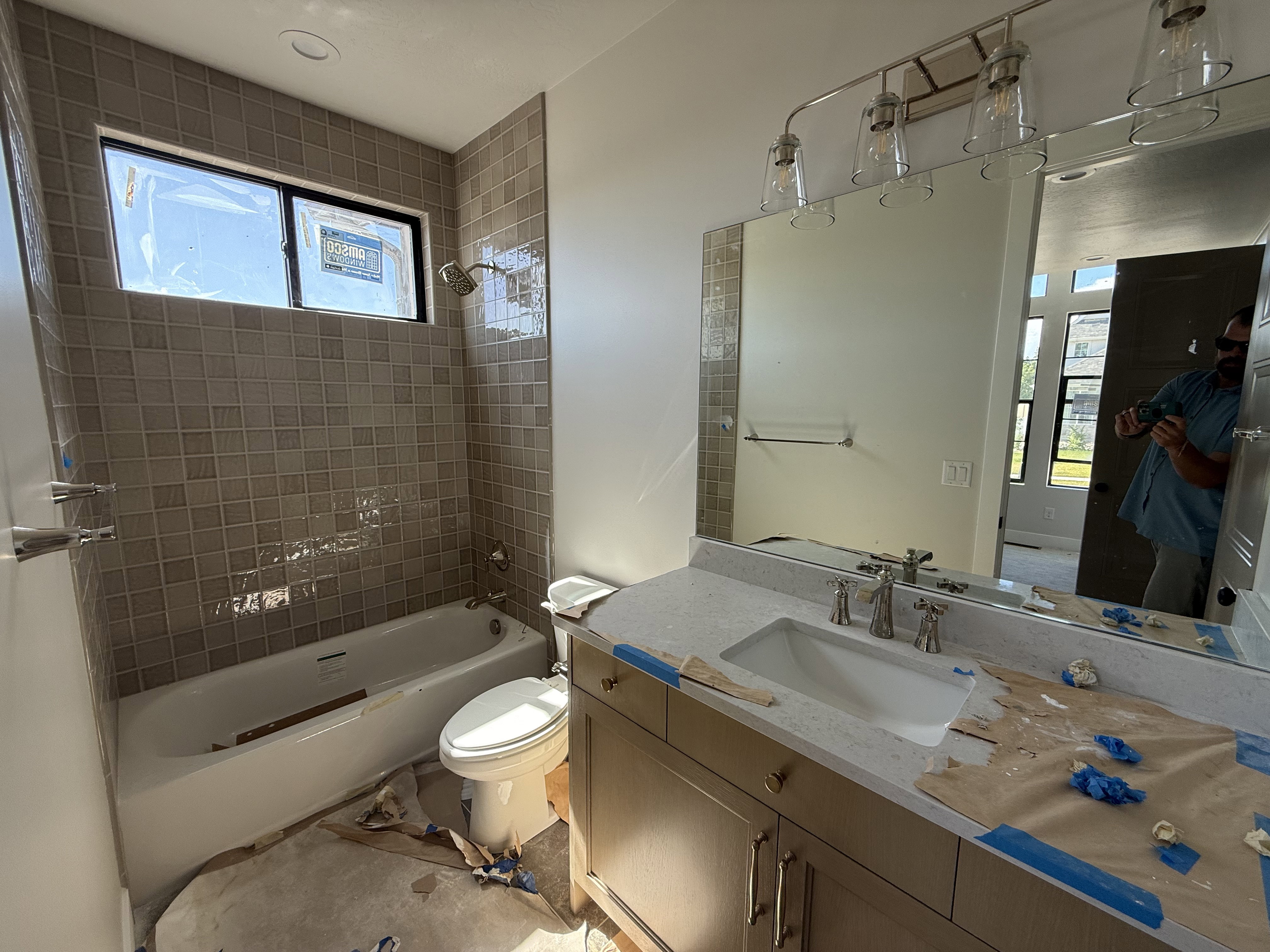 Bathroom featuring a vanity with an integrated sink, a large mirror, and a linear light fixture with clear glass shades