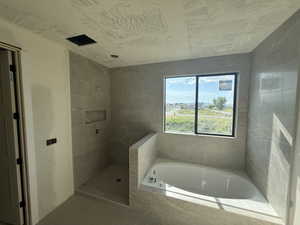 Full bath featuring tiled shower and a garden tub