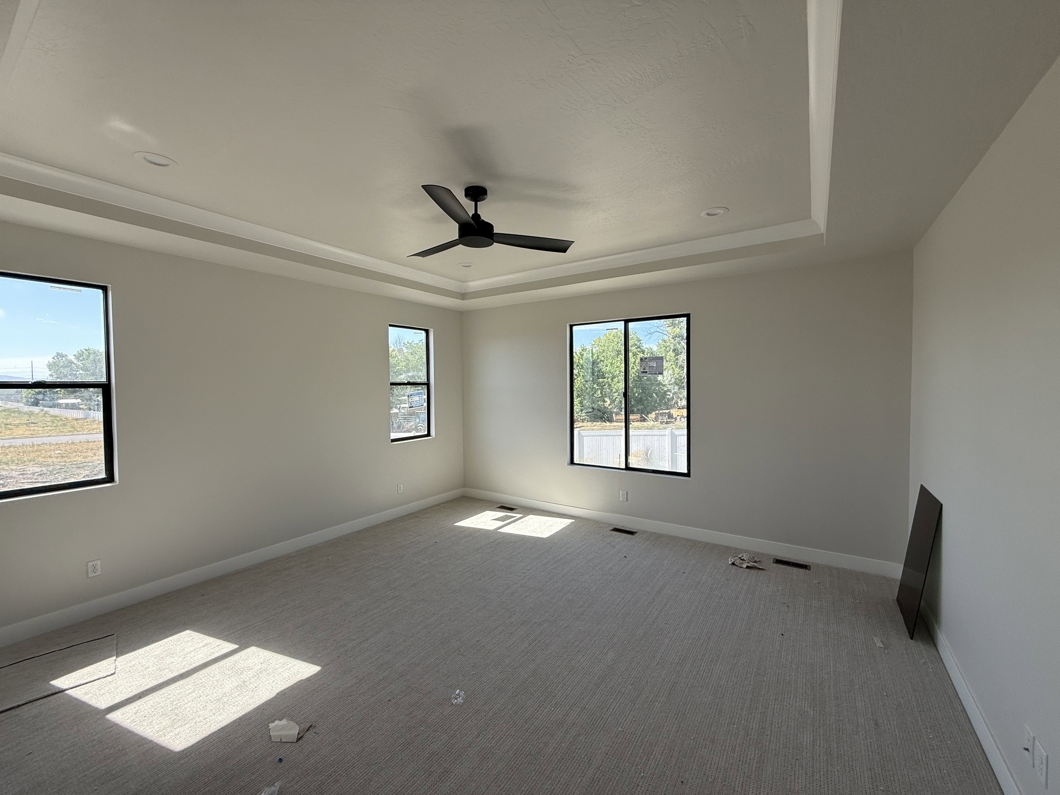 Spacious room featuring a tray ceiling with recessed lighting and a ceiling fan