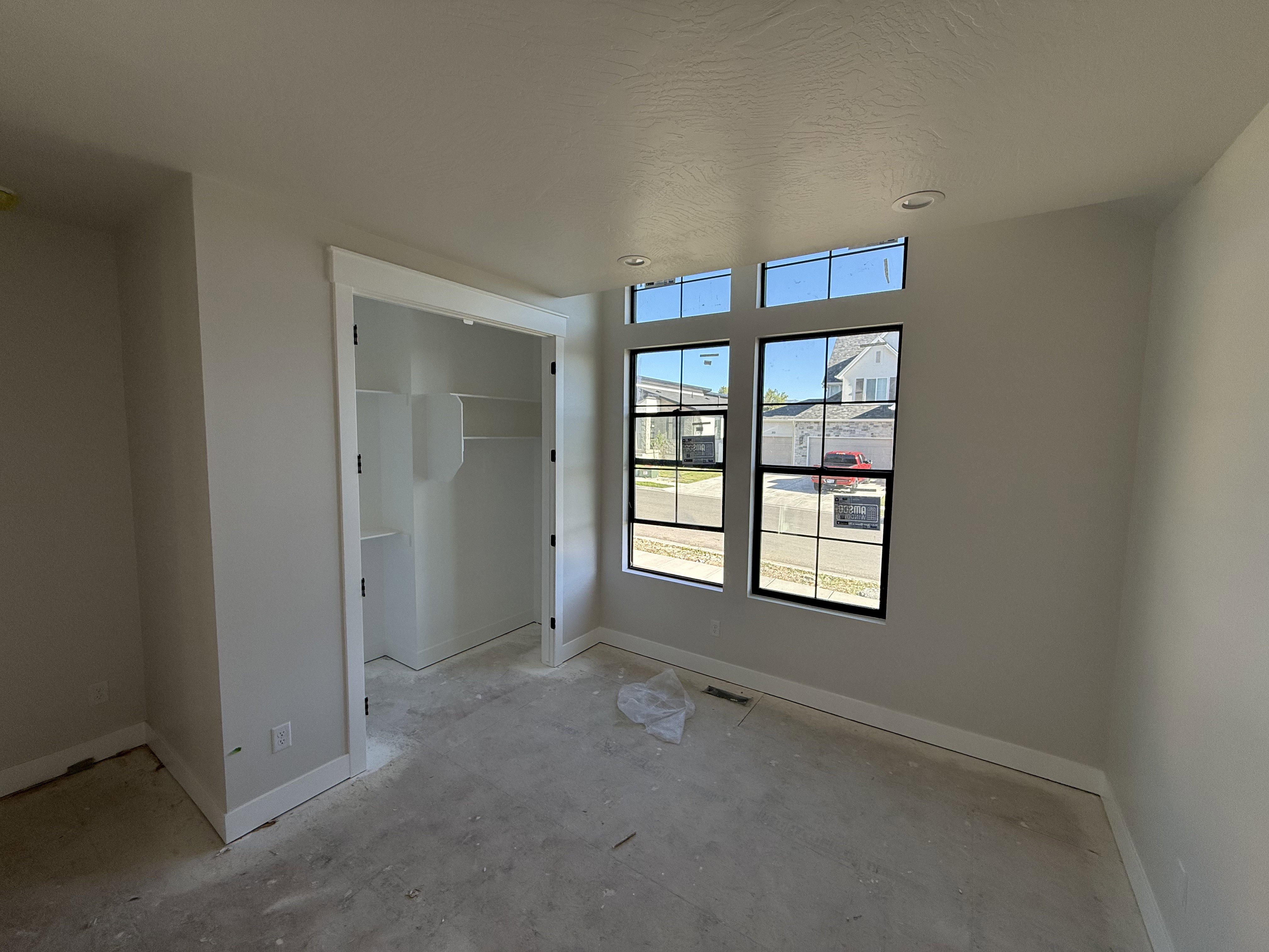 Room featuring multiple windows, recessed lighting, a built-in closet with shelving, light neutral wall tones, and white trim