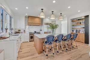 Kitchen featuring a kitchen breakfast bar, a center island, high end appliances, light stone counters, and two tone cabinetry