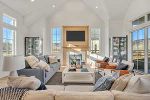 Living room featuring wood finished floors, recessed lighting, a premium fireplace, a high ceiling, and plenty of natural light