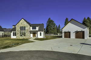 Modern farmhouse style home featuring stone siding, an outbuilding, and a garage