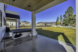 Fenced backyard featuring a patio, a mountain view, and a hot tub