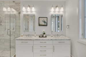 Bathroom with a marble finish shower and double vanity
