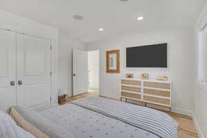 Bedroom featuring light wood-style flooring, recessed lighting, and a closet