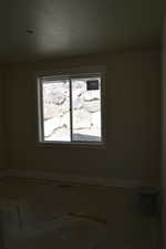 Unfurnished room with baseboards and a textured ceiling