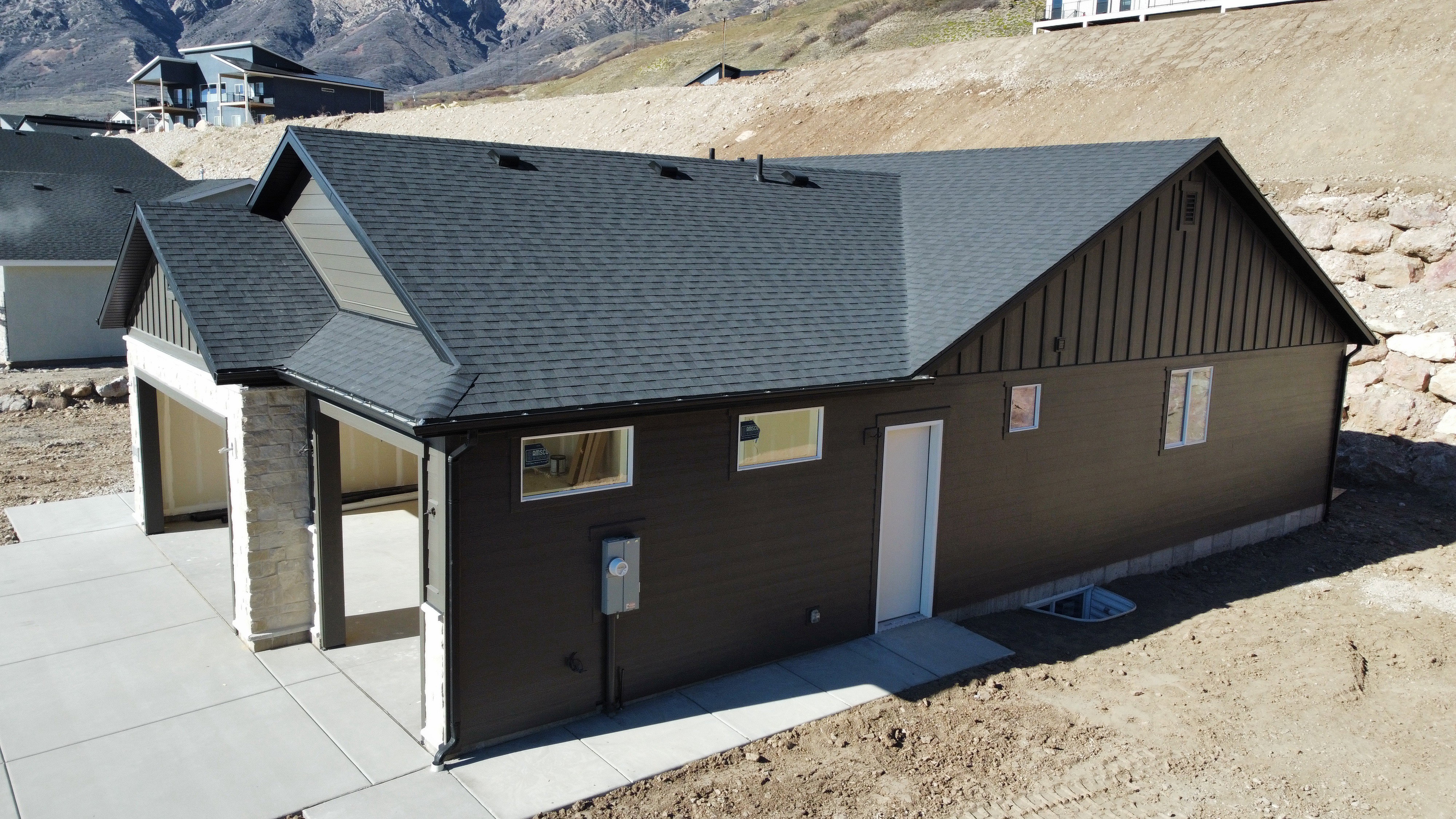 View of side of property featuring a shingled roof, board and batten siding, a mountain view, and stone siding