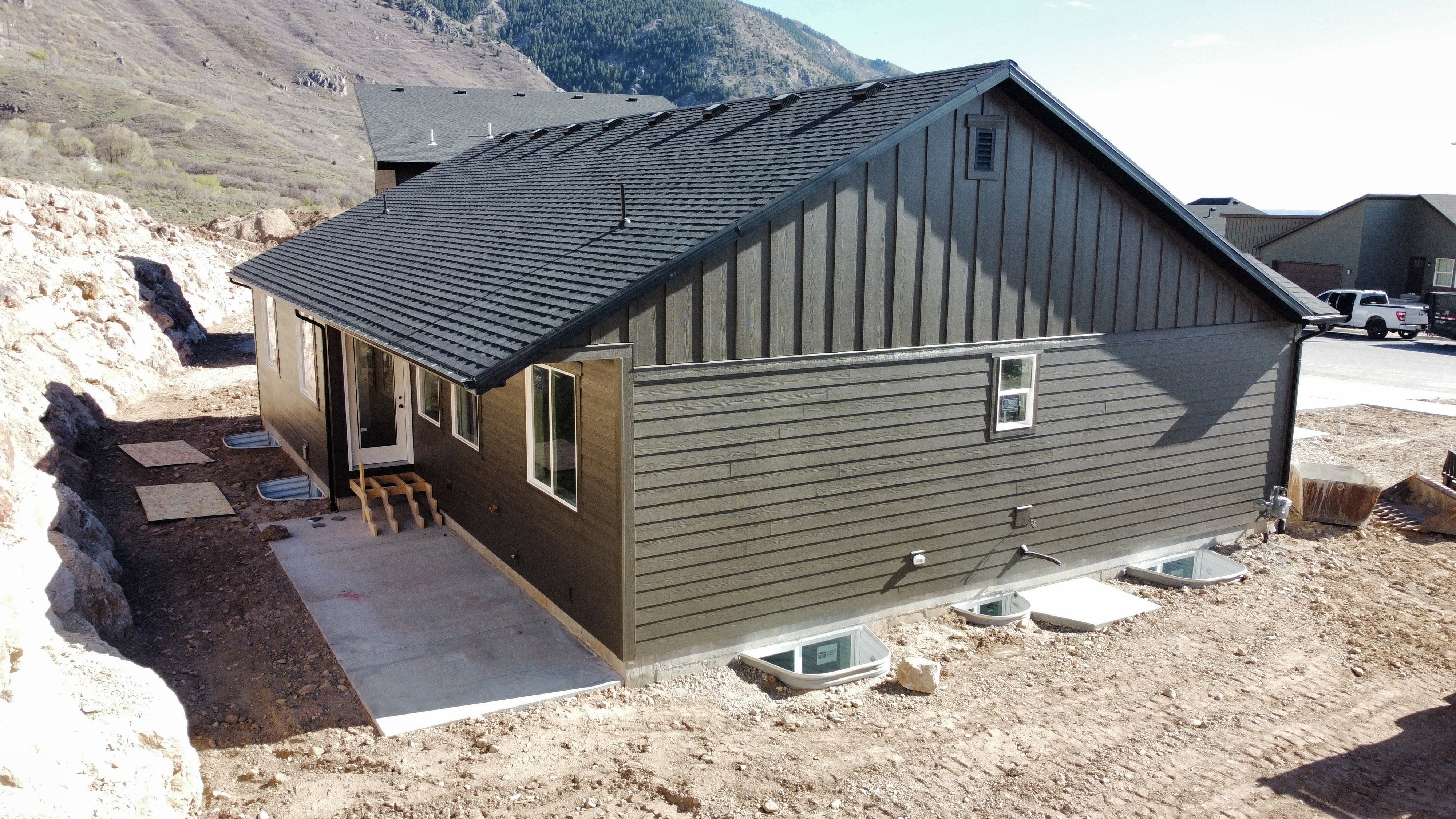 View of side of home with board and batten siding, a mountain view, and a patio