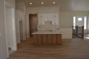 Kitchen featuring a kitchen island, two tone cabinets, recessed lighting, and wood finished floors