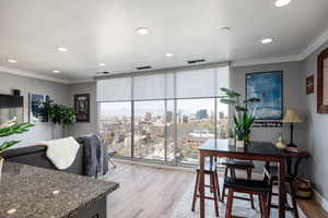 Dining room featuring light wood-style flooring, a city view, crown molding, recessed lighting, and floor to ceiling windows