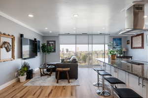 Living area featuring light wood-style flooring, floor to ceiling windows, recessed lighting, and crown molding