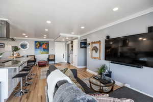 Living area featuring ornamental molding, light wood-style floors, and recessed lighting