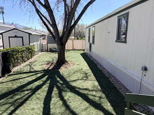 Fenced backyard featuring a storage unit