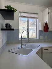 Kitchen featuring open shelves, light countertops, white dishwasher, and white cabinets