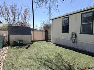 Fenced backyard featuring a shed