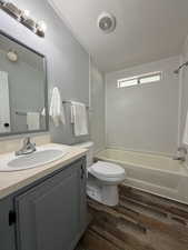 Bathroom with vanity, ornamental molding, tub / shower combination, dark wood finished floors, and a textured ceiling