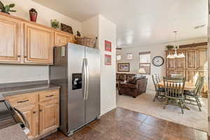 Kitchen featuring stainless steel refrigerator with ice dispenser, light wood finish cabinets, dark countertops, open floor plan, and electric range