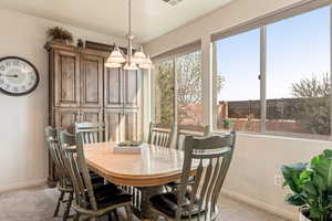 Dining area with light colored carpet and hanging lights