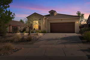 View of front facade featuring a garage, driveway, a tiled roof, and stucco siding