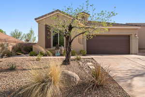 View of front of property with concrete driveway, an attached garage, stucco siding, and a tile roof