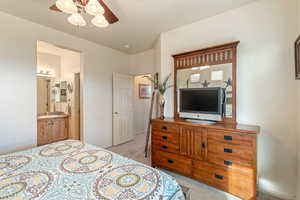 Bedroom with light colored carpet, a ceiling fan, and ensuite bathroom