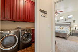 Laundry area featuring cabinet space, ceiling fan, separate washer and dryer, and dark carpet