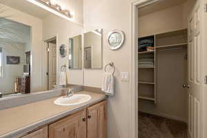 Bathroom featuring vanity, a spacious closet, and light carpet