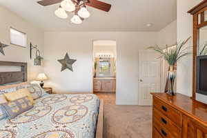 Bedroom featuring light carpet, ceiling fan, and ensuite bathroom
