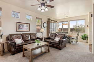 Living room with light colored carpet, a ceiling fan, plenty of natural light, and a textured ceiling
