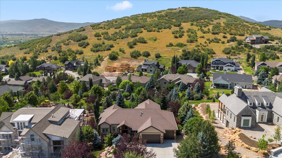 Aerial perspective of a developed residential area with mature landscaping, surrounded by expansive hills and distant mountains