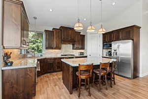 Kitchen with stainless steel appliances, granite countertops, travertine backsplash and dark wood finished cabinetry