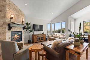 Living room featuring a stone fireplace, vaulted ceiling and healthy amount of natural light