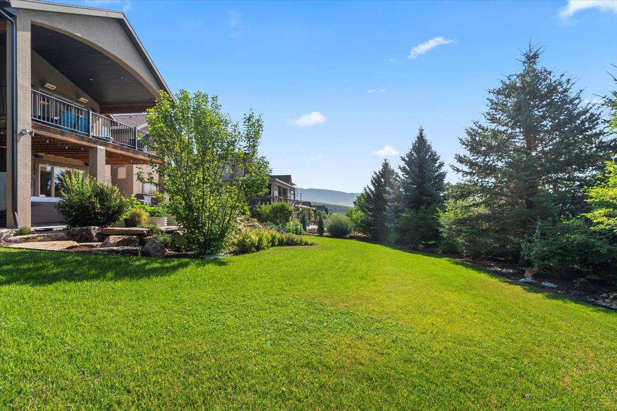 Expansive green lawn with mature evergreen trees bordering the property