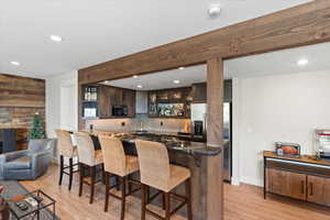 Lower level kitchenette with dark wood finished cabinets, granite countertop, stainless steel appliances and tile backsplash