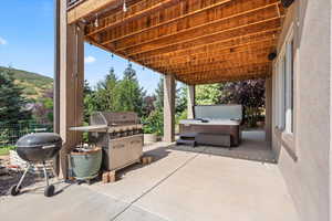 View of lower level, covered patio featuring a grill and hot tub