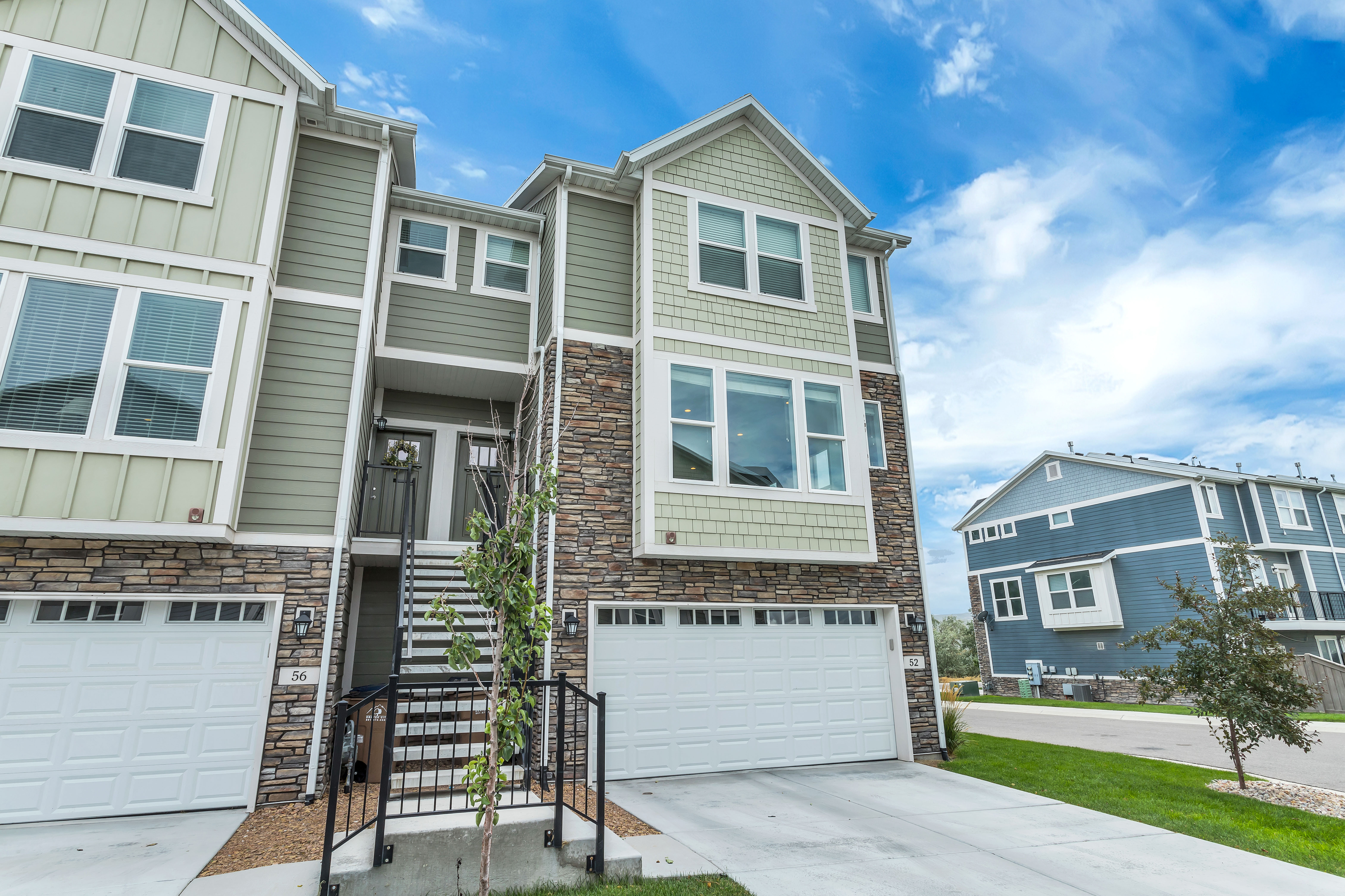 Craftsman inspired home featuring stone siding, board and batten siding, concrete driveway, a garage, and a residential view