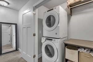 Laundry area featuring stacked washer and clothes dryer and a textured ceiling