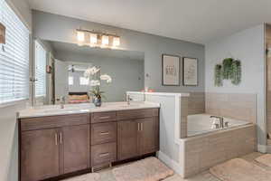 Ensuite bathroom featuring double vanity, a garden tub, a ceiling fan, and a shower stall